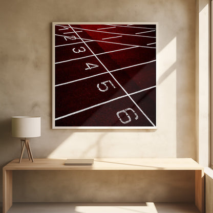 A framed, high-angle photograph of a deep red running track, showing the white lines and numbers for lanes one through six creating a grid-like pattern. Poster