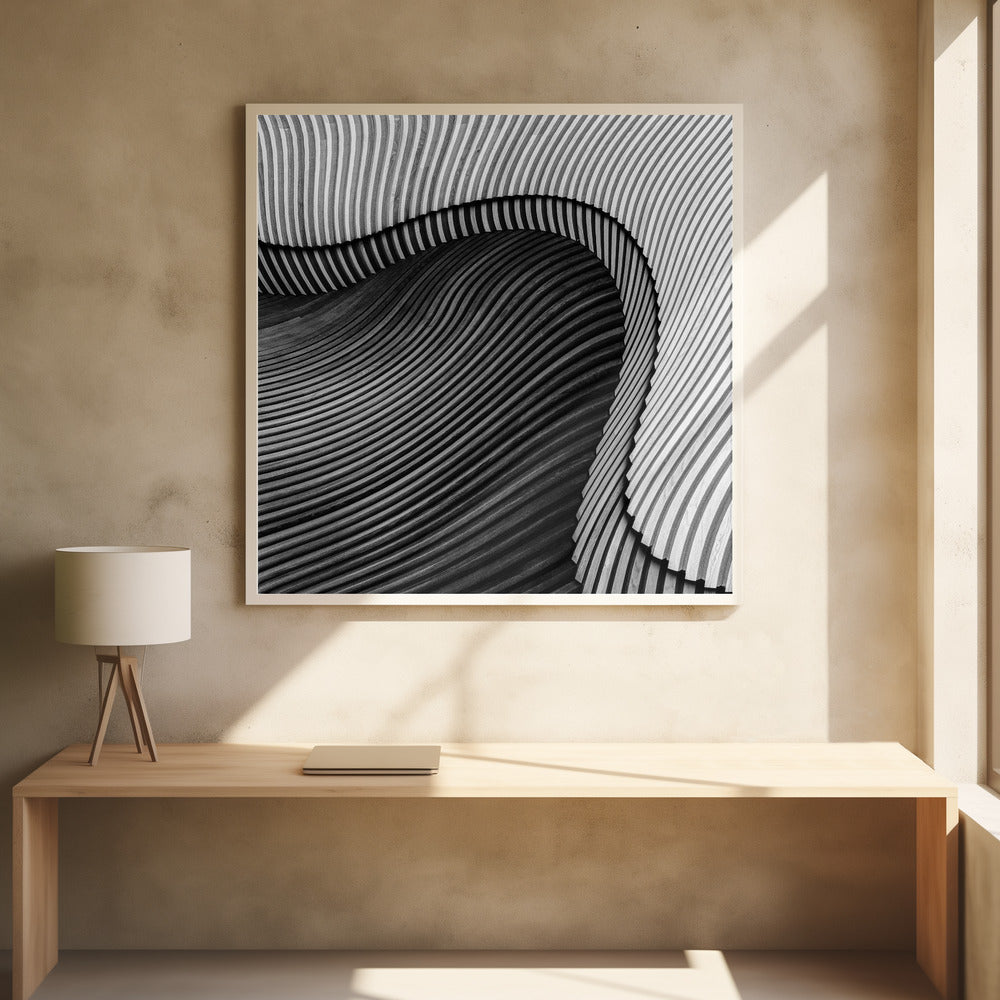 A square, black and white abstract photograph in a light wood frame. The image features layers of flowing, curved surfaces with parallel grooves, creating a strong sense of texture and depth. Lighter, striped layers with vertical lines curve over a darker, undulating section, resembling waves or sculpted wood, drawing the eye into a central dark crevice. Decor