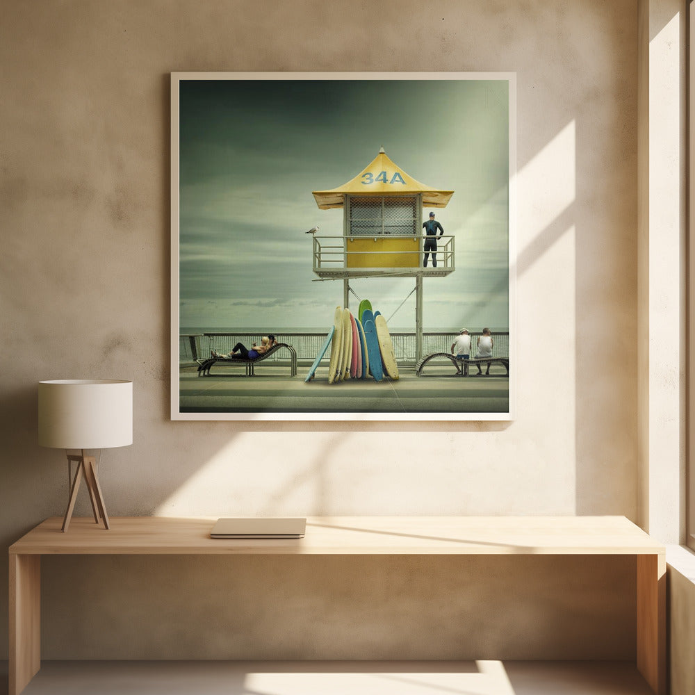A vintage-style photograph of a yellow lifeguard tower labeled '34A' on a beach boardwalk under an overcast, greenish sky. A lifeguard in a wetsuit stands on the balcony, while a collection of colorful surfboards leans against the base. People are seen relaxing on benches nearby. Print